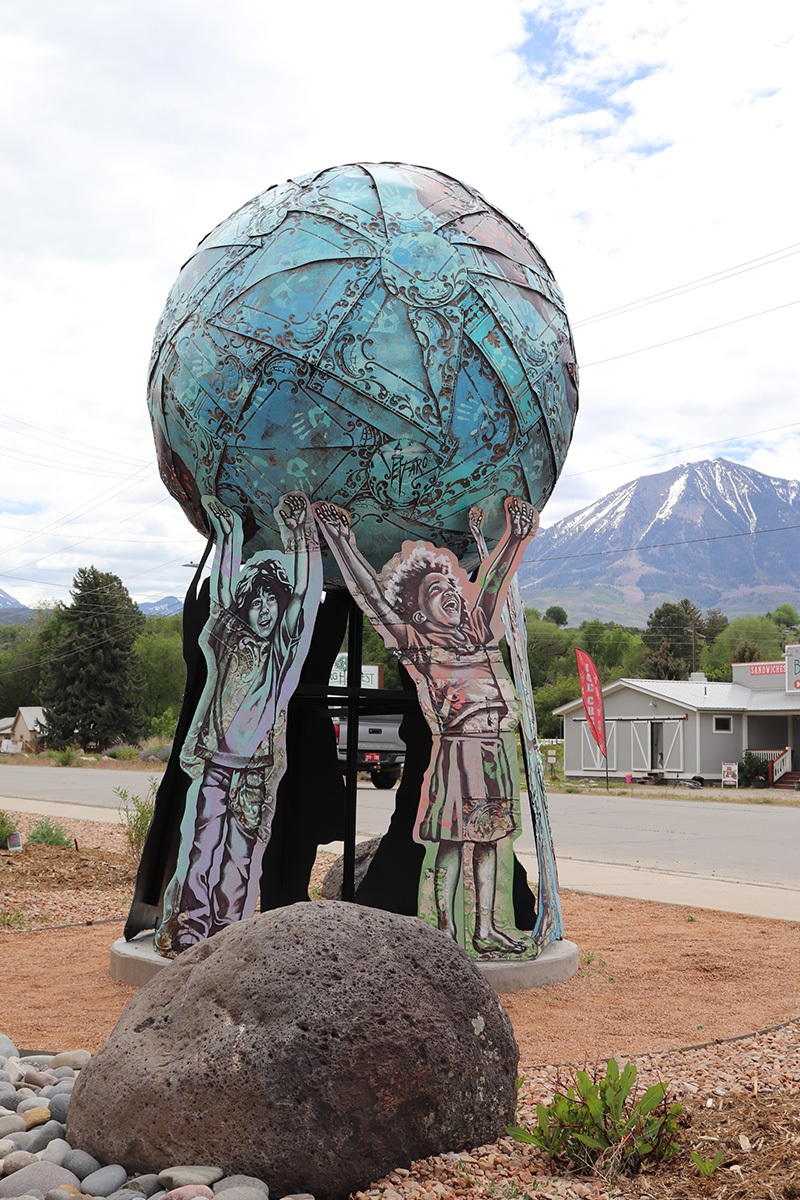 A metal sculpture depicting several children holding up the world globe. 