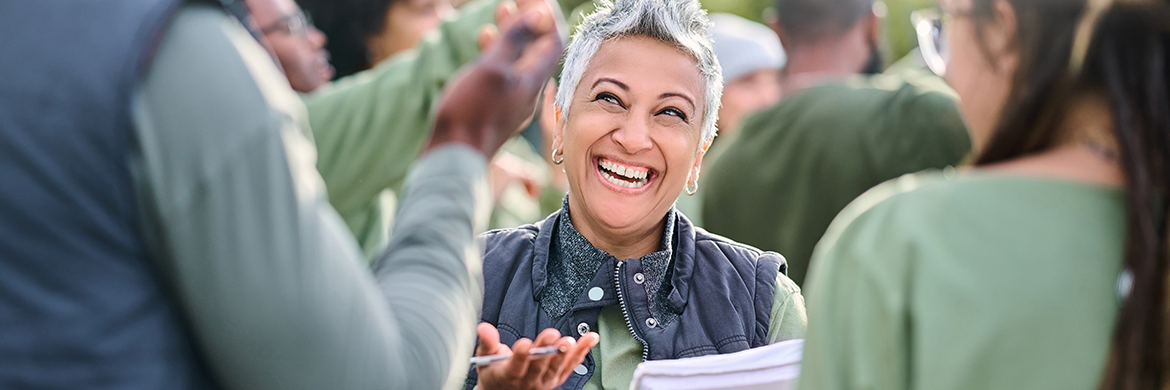 Woman smiling as she talks to a man and a woman during what appears to be a library event