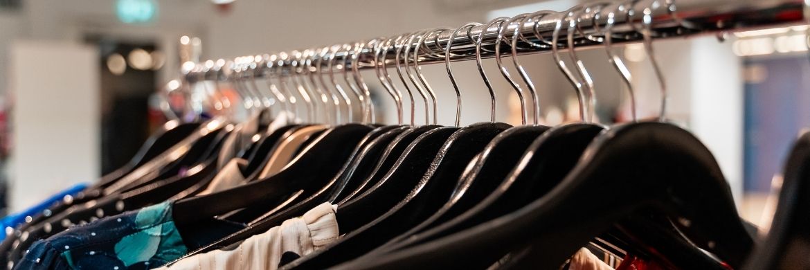 An abundance of clothing hangers are arranged on a clothes rack.