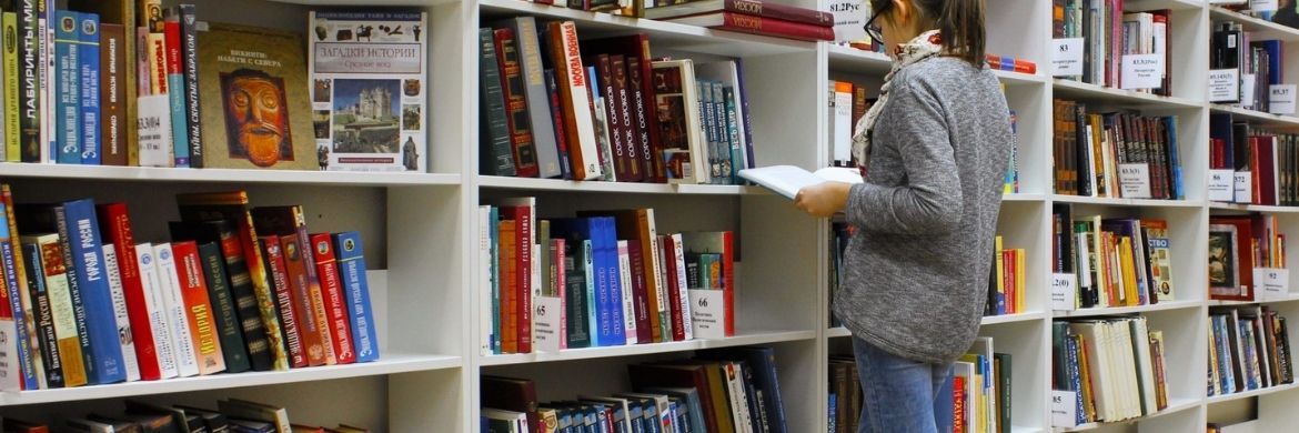 A patron browsing books on a wall-length shelf.