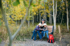 Woman and two boys with a family activity backpack on a bench at a state park