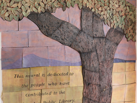 A textured mural of a tree greets patrons as they enter the library. Through the middle of the tree are the words "Tree of Knowledge".