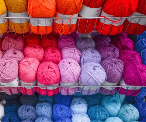 Image of a colorful array of spools of yarn ranging from bright yellow and orange through to deep blue in color.