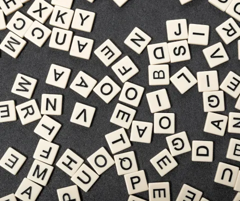Many various scrabble pieces cover a table with a black background.