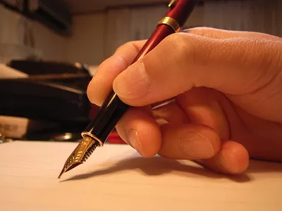 Hand holding a fountain pen and writing 