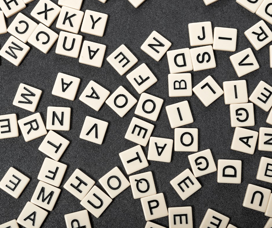 Many various scrabble pieces cover a table with a black background.
