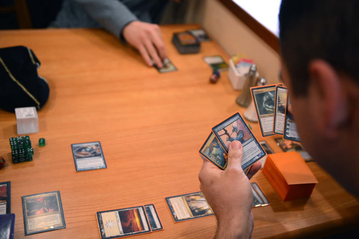 Two people playing Magic: the Gathering card game at a table.